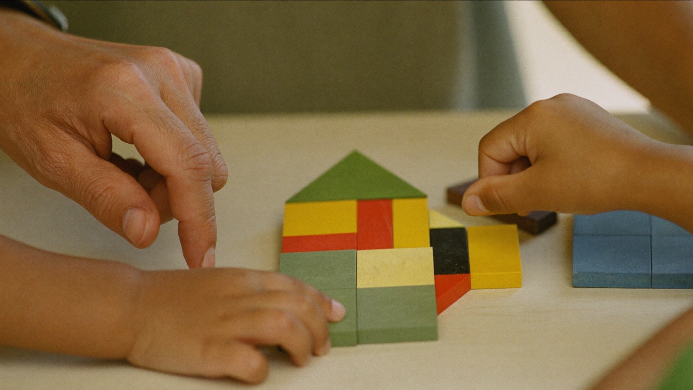 Manos de un niño jugando con piezas de madera durante una sesión de evaluación