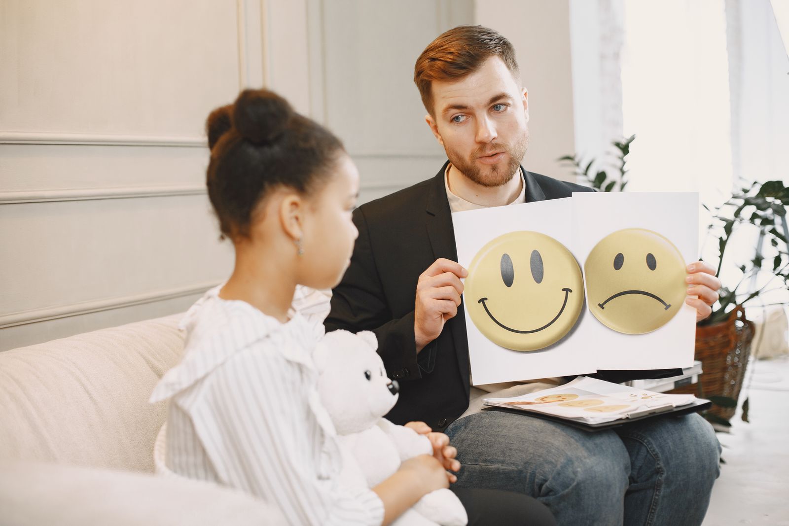 Profesional mostrando láminas de emociones a una niña durante una conversación