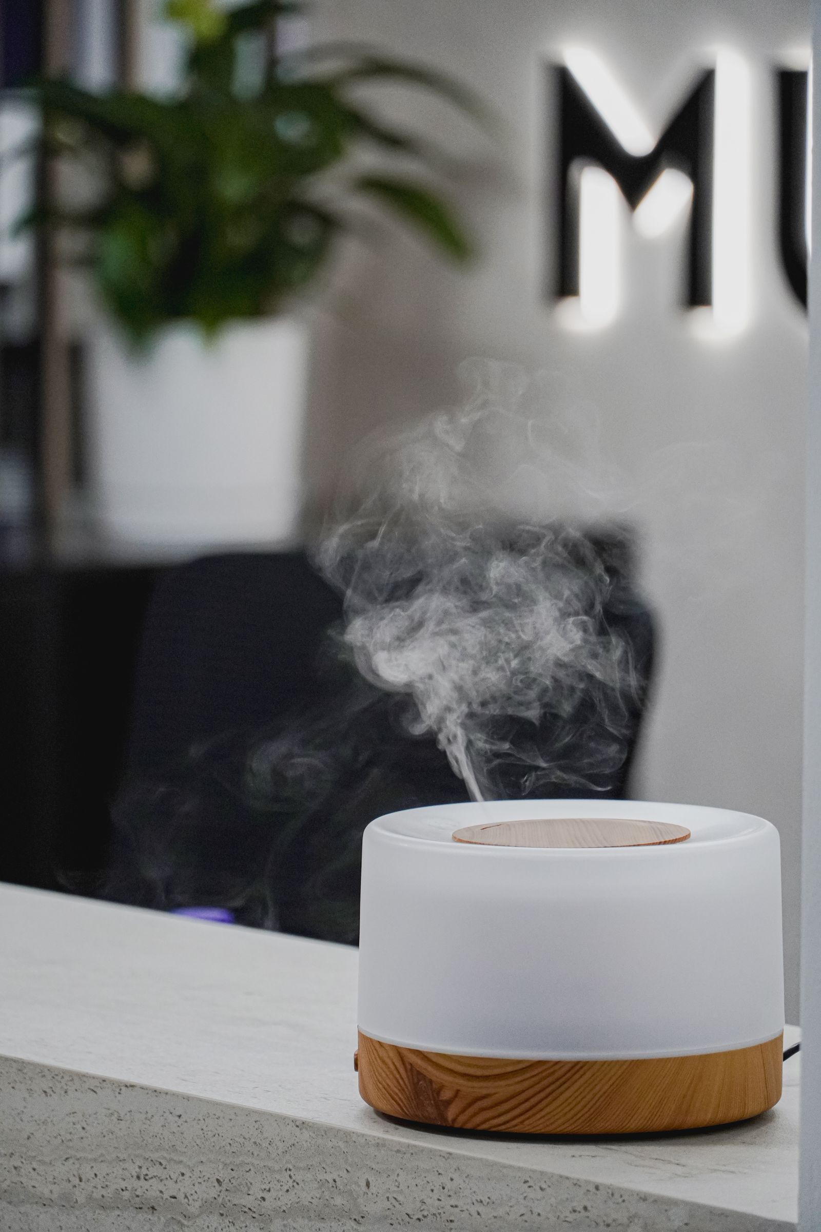 Difusor ultrasónico blanco y madera emitiendo vapor