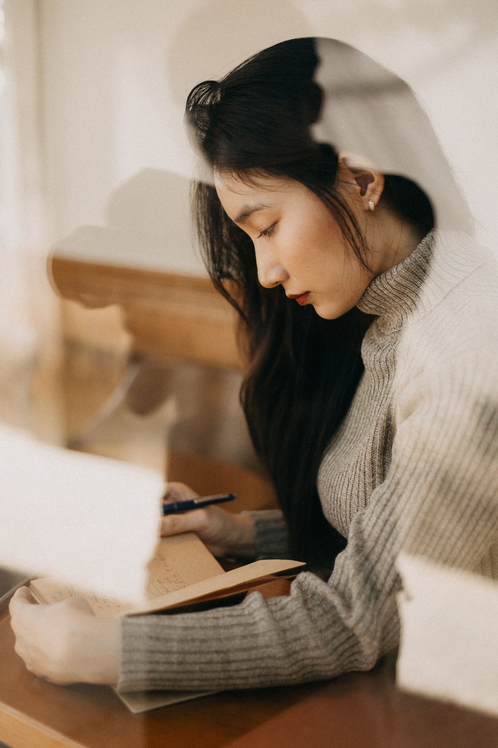 Mujer escribiendo en un cuaderno junto a una ventana