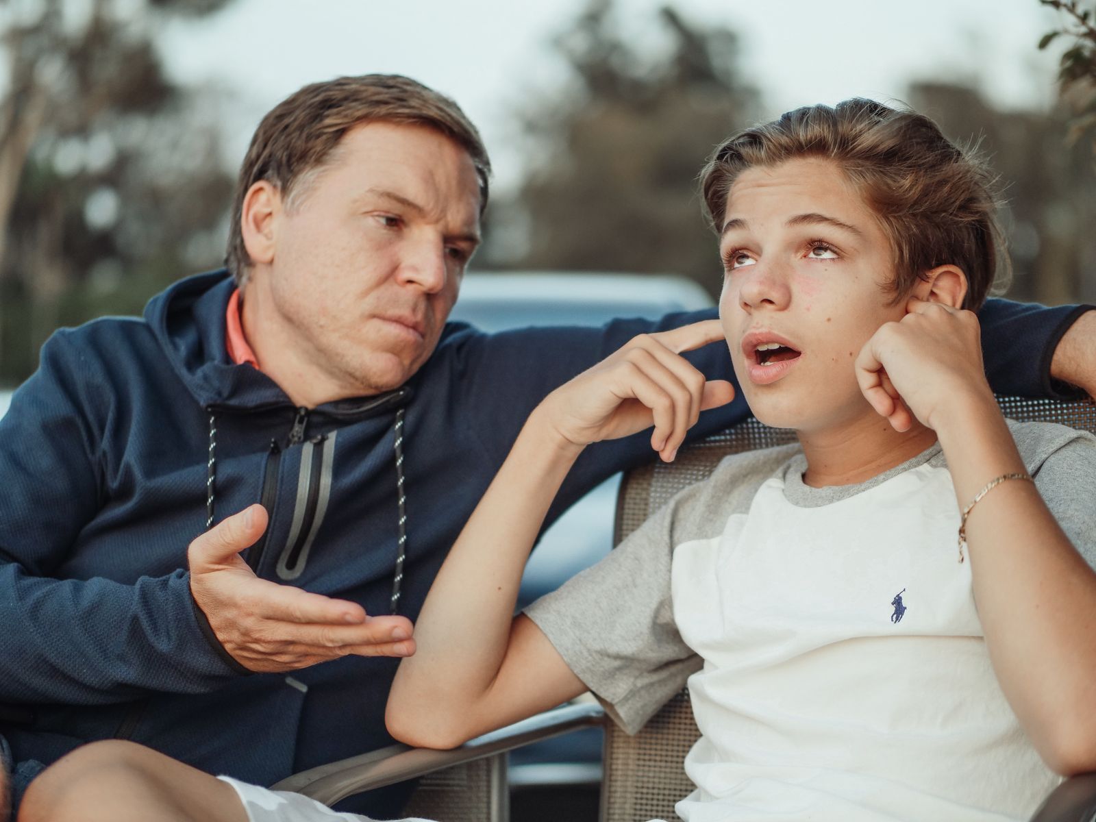 Padre conversando con su hijo adolescente al aire libre