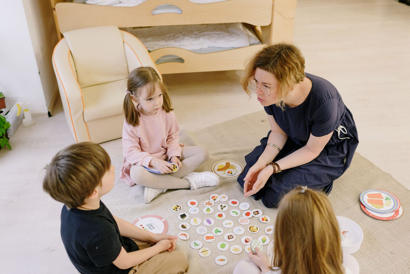 Adulta y tres niños participando juntos en un juego de mesa con cartas