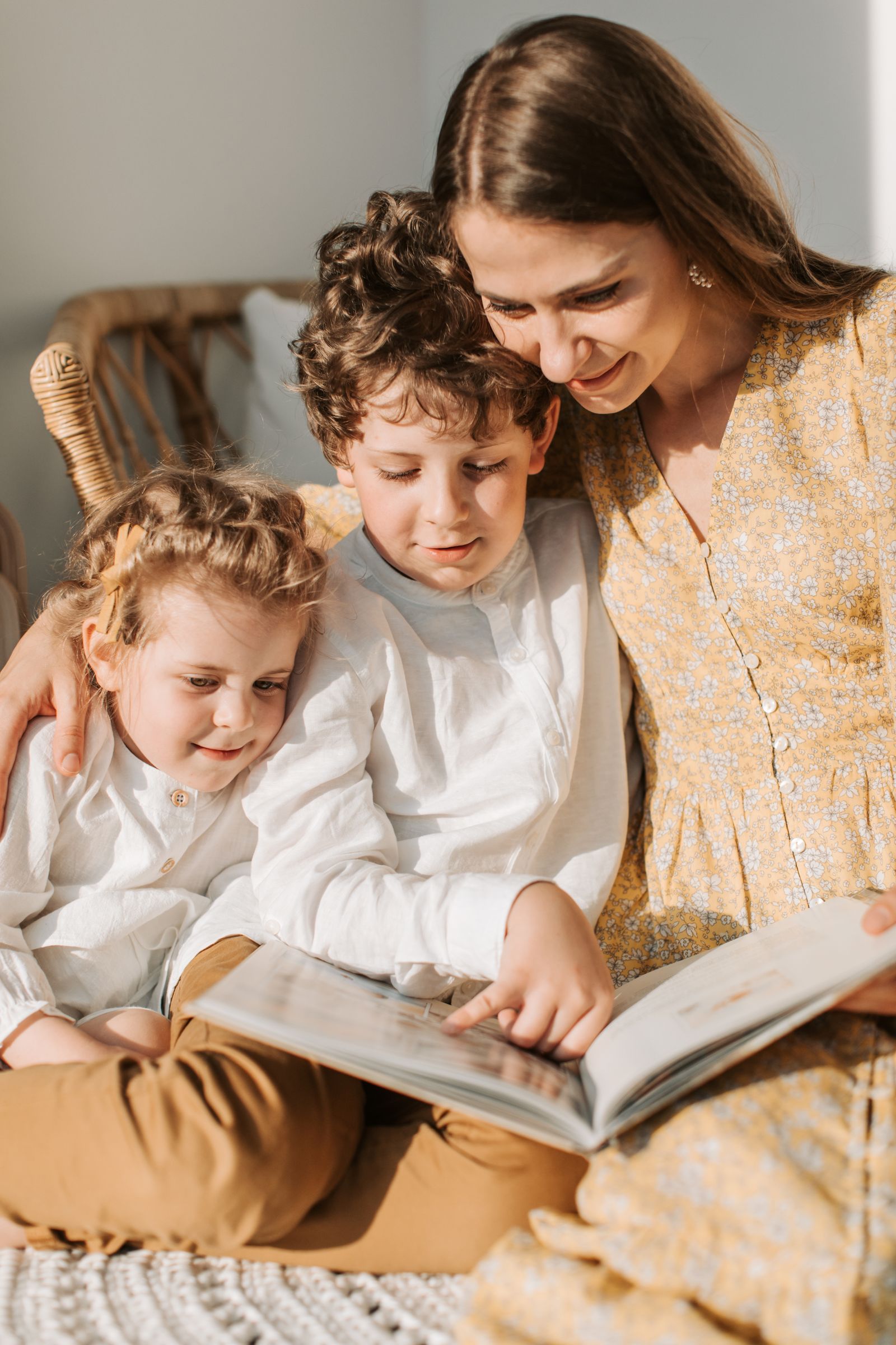 Madre leyendo un libro junto a dos niños en casa