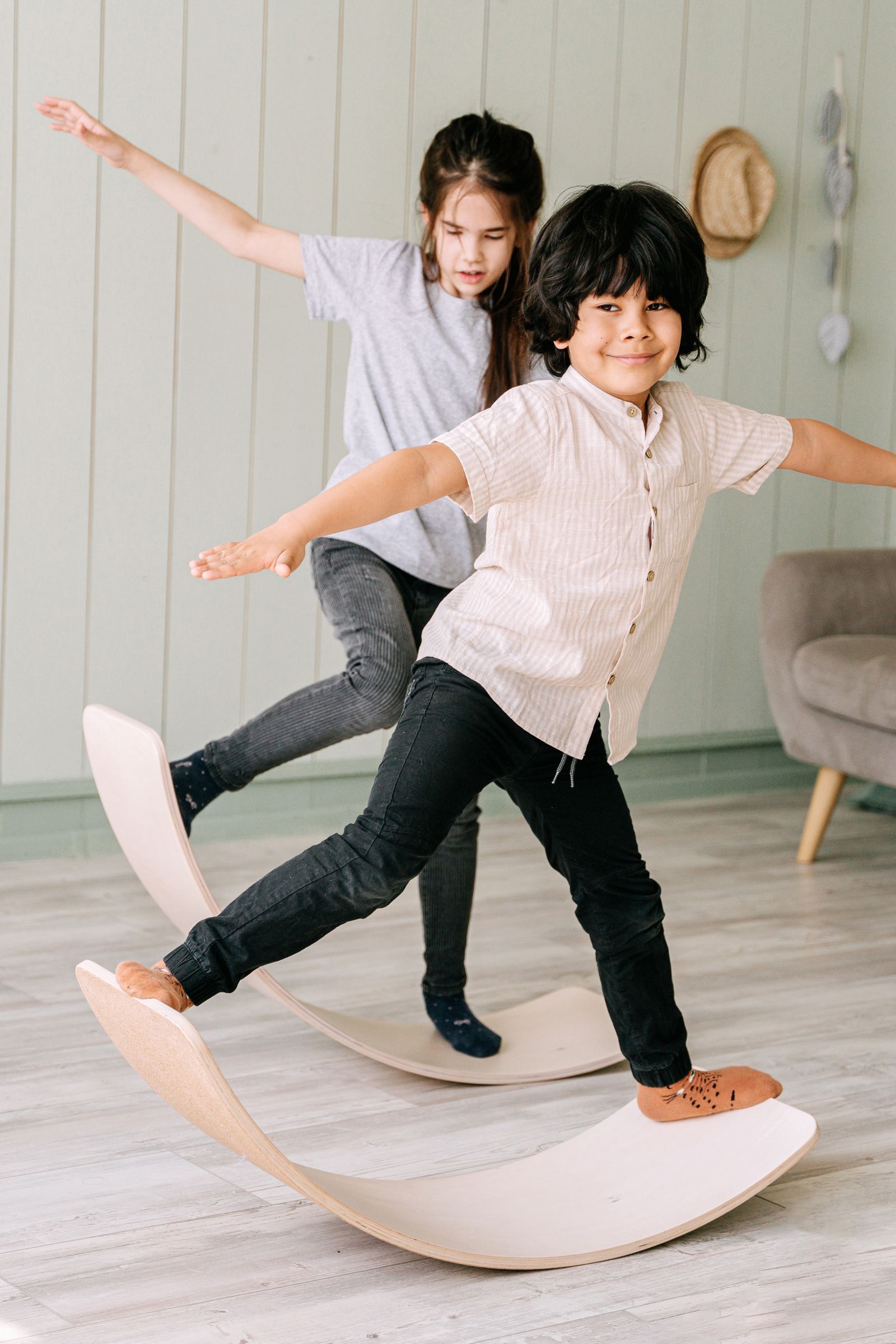 Dos niños jugando y manteniendo el equilibrio sobre tablas curvas de madera